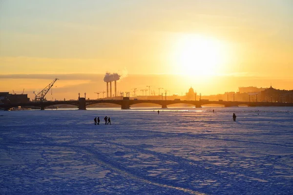 Annunciation Köprüsü manzarası, Neva nehrinin buzları üzerindeki insanlar ve Saint-Petersburg 'da kış akşamları gün batımı.