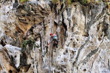 Genç kadın kayaya tırmanıyor.