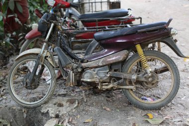 Arka planda paslı metal motosikletler, yakın plan.