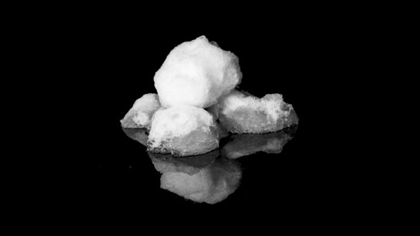 Drie sneeuwballen smelten op zwart reflecterend oppervlak, time-lapse studio shot — Stockvideo