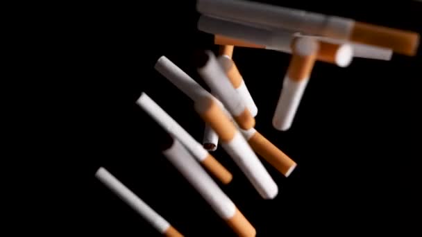 Top down shot of cigarettes falling into black background, studio shot. — Stock Video