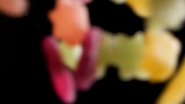 Colorful sour candy falling into dark abyss in slow motion, studio shot. — Stock Video