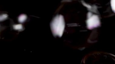 Sabun köpüklerini siyah arkaplanda yavaş çekimde üfle.