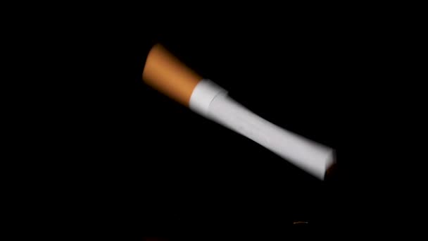 Jedna cigareta padající a poskakující na černém reflexním povrchu ve zpomaleném pohybu. — Stock video