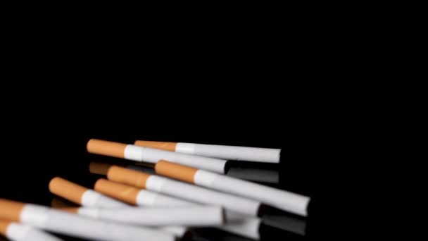 Pile of cigarettes are rolled out on a black mirroring surface in slow motion. — Stock Video