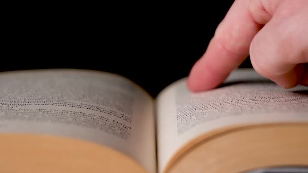 Degetul alb caucazian caută un cuvânt într-o carte și îl rotește . — Videoclip de stoc