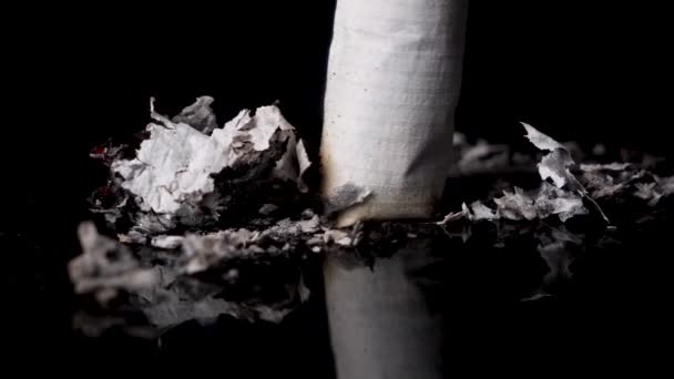 Macro stub out a cigarette on black surface in slow motion, isolated — Stock Video