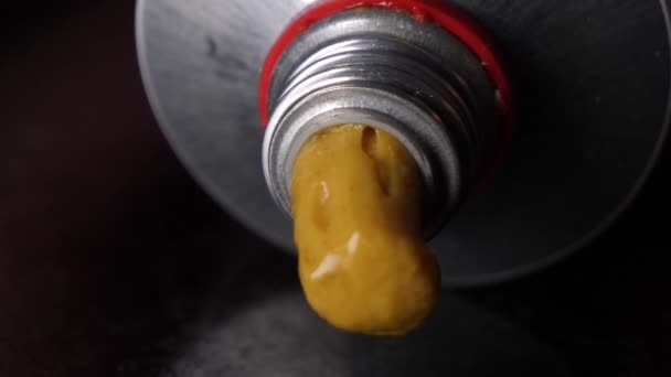 Macro shot of yellow mustard flowing out of a tube, concept of defecate — Stock Video