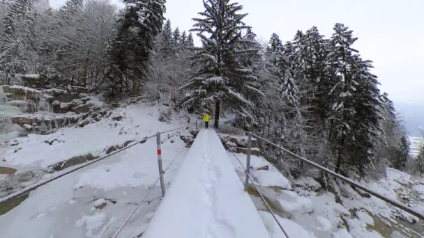 Hombre caucásico camina sobre puente nevado en Suiza, pan de izquierda a derecha — Vídeos de Stock