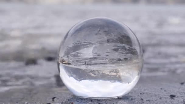 Vista de las montañas suizas en una bola de lente que yace en la arena en una playa. — Vídeos de Stock
