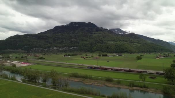 Drone siguiendo un tren en movimiento que conduce a un hermoso panorama del lago de montaña. — Vídeo de stock