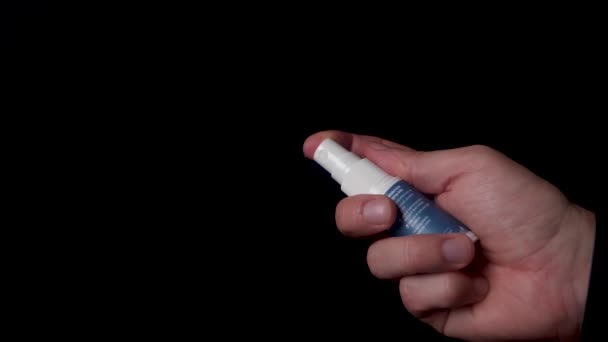 Spraying a vegan vitamin D spray on the camera, isolated black background — Stock Video
