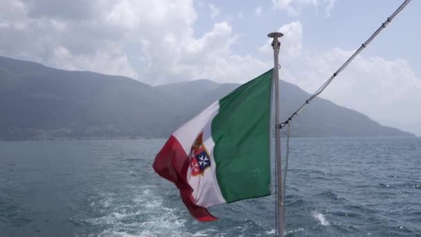 Bandera italiana ondeando en el viento frente a una gran montaña en el lago Maggiore — Vídeo de stock