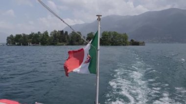 Brissago 'dan ayrılan bir teknenin rüzgarında sallanan armalı İtalya bayrağı..