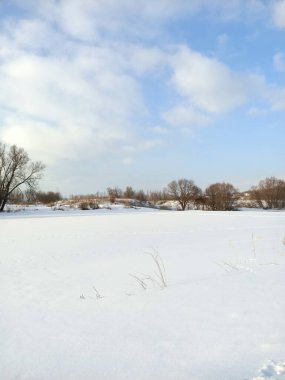 Nehrin buzunun üzerindeki beyaz kar tarlası Mavi gökyüzünün altında bulutlarla