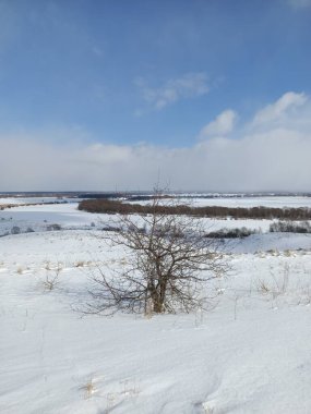 Nehrin buzunun üzerindeki beyaz kar tarlası Mavi gökyüzünün altında bulutlarla
