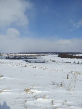 Nehrin buzunun üzerindeki beyaz kar tarlası Mavi gökyüzünün altında bulutlarla