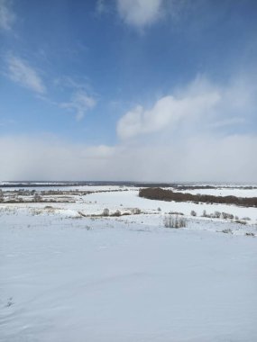 Nehrin buzunun üzerindeki beyaz kar tarlası Mavi gökyüzünün altında bulutlarla