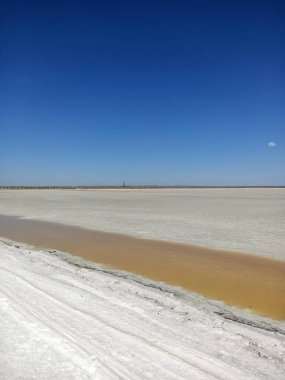 Pembe gölde, mavi gökyüzünün altında tuz kıyıları olan sarı nehir.