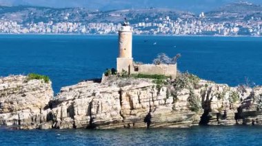 Panagitsa adasındaki eski deniz fenerinin sinematik tavası, Korfu, Yunanistan ve Arnavutluk arasındaki sınırı işaret ediyor. Kıyı kenti arka planına sahip pitoresk bir Avrupa tatil beldesi