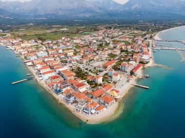 İyon Denizi 'nde bir yarımadadaki sakin bir Yunan köyü olan Mytikas' ın havadan görünüşü, kırmızı çatılı evler, liman, dağlar ve turkuaz su ile çevrili..