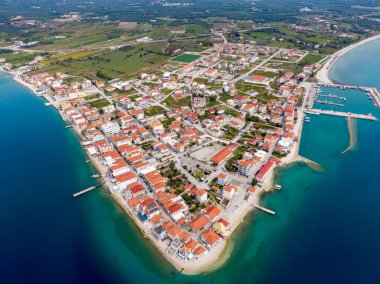 İyon Denizi 'nde bir yarımadadaki sakin bir Yunan köyü olan Mytikas' ın havadan görünüşü, kırmızı çatılı evler, liman, dağlar ve turkuaz su ile çevrili..