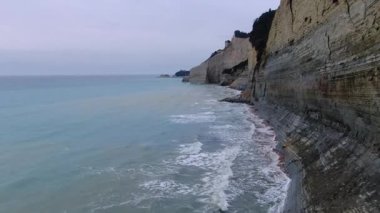 Korfu 'daki Loggas Sahili' nin engin uçurumlarında uçan insansız hava aracı görüntüleri. Turkuaz deniz dalgaları uzak bir Yunan kıyı şeridine çarpıyor