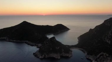 Yunanistan 'ın Korfu kentindeki Porto Timoni İkiz Sahili' nde Canlı Turuncu Günbatımına karşı Destansı Hava Aracı Yörüngeleri Silueti