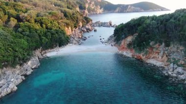 Hava aracı, turkuaz suyun üzerinden Yunanistan 'daki orman kayalıklarıyla çevrili çarpıcı, tenha beyaz çakıl taşı plaj koyuna uçarken görüntüler çekti.