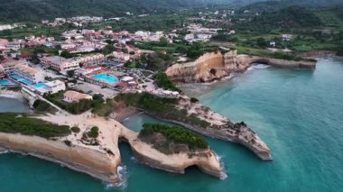 Sidari, Corfu, Yunanistan 'ın yüksek irtifadaki insansız hava aracı yörüngesinde ünlü Kanal d' Amour kayalıklarını ve tüm sahil kasabasını gösteriyor.