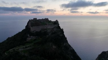 Angelokastro kalesinin hava yörüngesi alacakaranlıkta yüksek uçurumunda, çarpıcı Paleokastritsa kıyısı ve Yunanistan 'ın Korfu kentindeki İyon Denizi' ni gözler önüne seriyor.