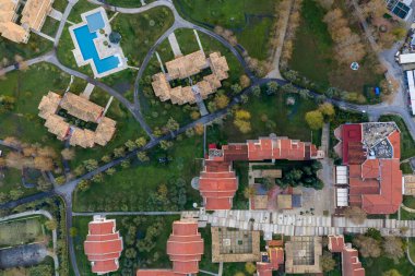 Lüks bir otel otelinin tepeden aşağı insansız hava aracı görüntüsü, yüzme havuzlarını, çatıları ve yeşil zemini gösteriyor.