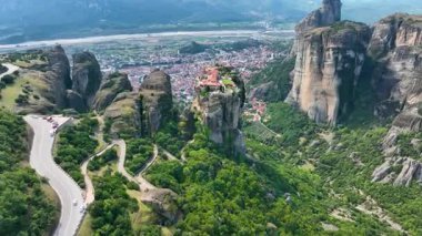 Yunanistan 'ın Meteora kentindeki Kutsal Üçlemeci Manastırı' na yaklaşan geniş çaplı bir hava aracı atışı. Vadinin aşağısındaki virajlı yolları, uçurumları ve Kalabaka kasabasını gösteren bir çekim.