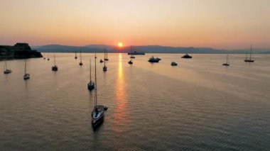 Güzel Gündoğumu ya da Denizde Gün batımı Yelkenli ve Korfu 'nun Eski Kalesi' nin yakınına demirlenmiş yolcu gemileri
