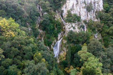 Pagi Korfu 'da şelale deresi olan yüksek kireçtaşı uçurumu Yunanistan İyon doğasının yabani bitki örtüsü hava aracıyla çevrili