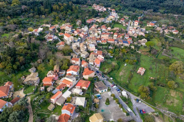 Korfu 'daki Pagi köyü meydanı ve kilisesinin insansız hava aracı manzarası yeşil tarlalar ve geleneksel İyon evleriyle çevrili