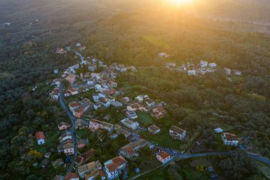 Kırmızı kiremit çatılı geleneksel bir Yunan köyünün havadan aşağı manzarası. Altın saat güneş ışığı Corfu 'daki evlere ve zeytin ağaçlarına vuruyor.