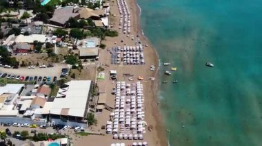 Kalabalık kumlu kumsalın yukarıdan görünüşü beyaz şemsiyeler, güneşlik yataklar ve turkuaz deniz suyu, yaz tatili tatil beldesi.