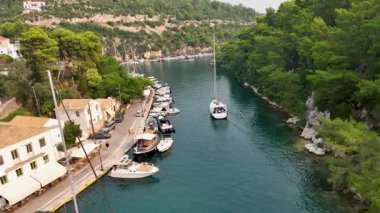 Pine Trees ve Antika Liman Restoranları ve Dükkanlarıyla çevrili Yunanistan 'ın Gaios, Paxos Adası' nın Dar Suyu Yolu 'nda Gezinen Bir Yelkenlinin Manzarası