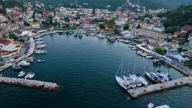 Korfu 'daki Kassiopi' nin at nalı şeklinde limanının insansız hava aracı görüntüsü Yunanistan 'da yelkenli yatlar ve restoranlarla çevrili balıkçı tekneleri ile dolu.