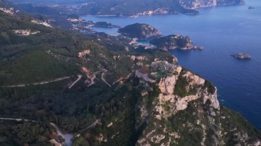 Angelokastro Bizans şatosunun İyon Denizi ve Paleokastritsa körfezi kıyı şeridine bakan yüksek kayalık tepe üzerindeki havadan görünüşü yaz akşamı Yunanistan 'ın Korfu adası boyunca harabeye döndü.