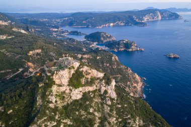 Yunan Angelokastro kalesinin batı kıyı şeridine ve Yunanistan 'ın Korfu derin mavi İyon Denizi' ne bakan kayalık bir tepedeki dikey hava kompozisyonu