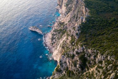 Yunanistan 'ın Korfu Adası' nın engebeli batı kıyısındaki turkuaz İyon Denizi 'ne düşen sarp kayalıkların hava manzarası dramatik jeolojik oluşumları ve derin mavi suları gösteriyor.