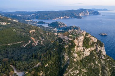 Tarihi Angelokastro kalıntılarını barındıran geniş hava manzarası, Paleokastritsa 'nın dolambaçlı kıyı koyları ve Yunanistan' ın Korfu kentindeki mavi denizle birlikte bir uçurum üzerinde yer alıyor.