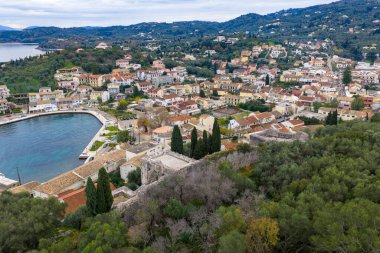 Kassiopi limanının panoramik hava aracı görüntüleri ve Korfu Yunanistan 'daki şato harabeleri, tekneli manzaralı kıyı köyü