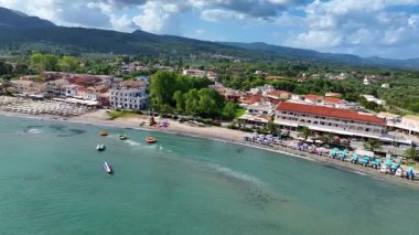 Kuzey Korfu 'daki kıyı otelleri ve dairelerin İyon Denizi' ne bakan yeşil bahçeli ve palmiyeli hava aracı manzarası