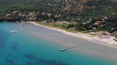 Kuzey Korfu Yunanistan 'daki uzun kumlu Apraos plajının havadan görüntüsü sığ turkuaz su, ahşap iskele ve çocuklar için şişirilebilir su parkı yaz tatili beldesi
