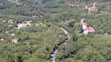 Yunanistan 'ın Korfu Adası kırsalındaki sık zeytin ağaçlarından oluşan bir ormanı kesen dolambaçlı bir asfalt yolun hava aracı görüntüleri Akdeniz' in verimli manzarasını ve doğasını gözler önüne seriyor..