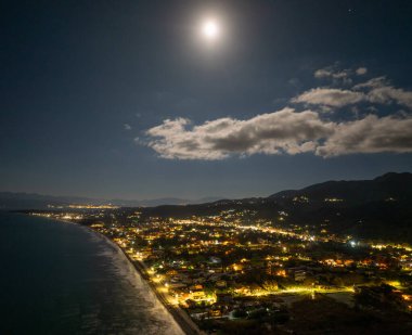 Korfu 'daki Acharavi Sahil Kasabası' nın Hava Gecesi Manzarası Dolunay ve Long Beach üzerindeki Bulutlar, Aydınlanmış Sahil Resort ve Köy Işıkları