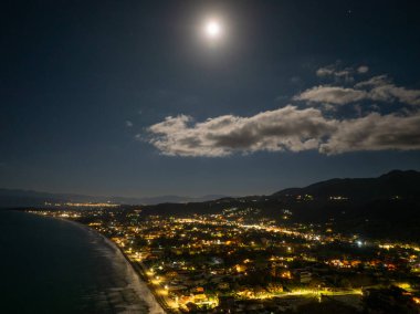 Korfu 'daki Acharavi Sahil Kasabası' nın Hava Gecesi Manzarası Dolunay ve Long Beach üzerindeki Bulutlar, Aydınlanmış Sahil Resort ve Köy Işıkları